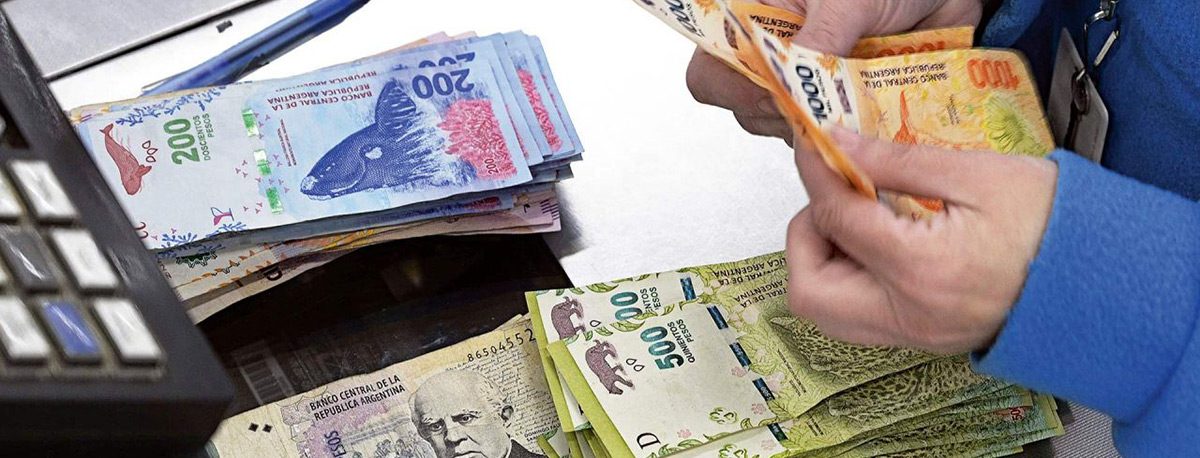 Persona contando billetes de pesos argentinos